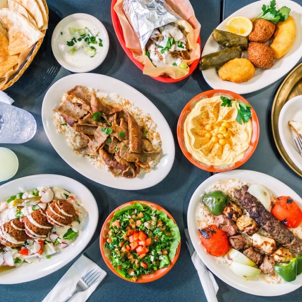 Overhead view of a table laden with various Middle Eastern dishes including kebabs, falafel, hummus, and shawarma.