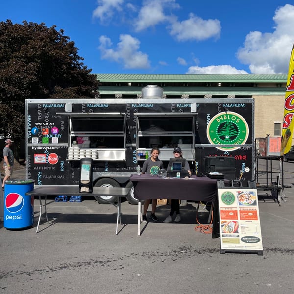 Byblos Mediterranean Cafe food truck with two employees, a Pepsi cooler, and a menu board.